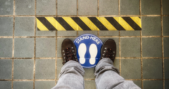 person standing in a social distance floor sticker